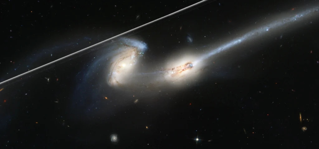 Hubble image of two interacting galaxies crossed by a bright satellite trail
